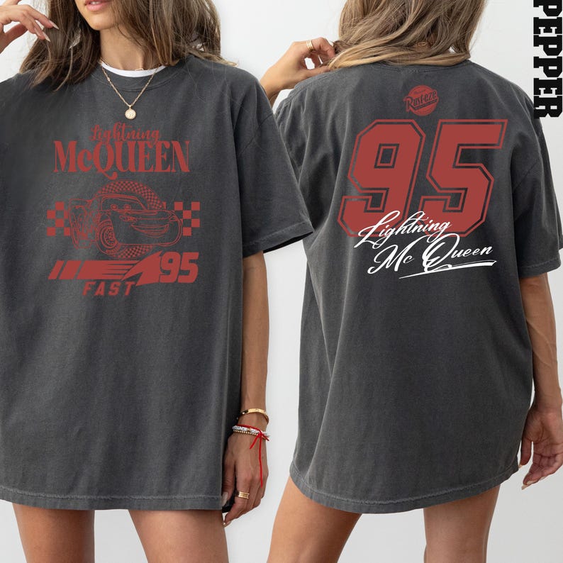 May include: A gray oversized t-shirt with a red graphic of a race car and the text "Lightning McQueen #95 Fast" on the front. The back of the shirt has a red number 95 and the text "Lightning McQueen" in a cursive font.