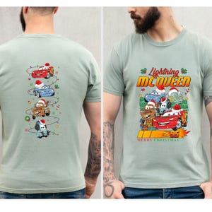May include: A pale green t-shirt with a festive design featuring Lightning McQueen and other Cars characters. The front displays "Lightning McQueen" and "Merry Christmas". The back shows a vertical arrangement of the Cars characters.