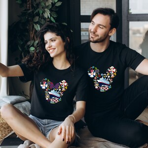 Pu&ograve; includere: T-shirt nere con un colorato design a forma di testa di Topolino riempito di elementi nautici, tra cui una nave da crociera, ancore e personaggi dei cartoni animati. Il design &egrave; nei toni del blu, rosso, giallo e bianco.