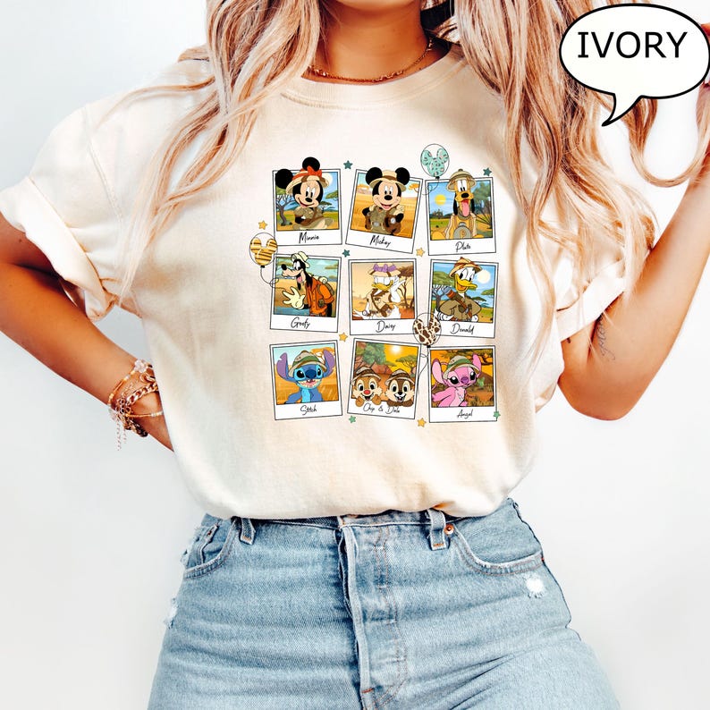 Puede incluir: Una camiseta blanca con un collage de personajes de Disney con atuendos de safari. Los personajes incluyen a Mickey Mouse, Minnie Mouse, Pluto, Goofy, Daisy Duck, Donald Duck, Stitch, Chip, Dale y Angel. La camiseta tiene un color marfil claro.