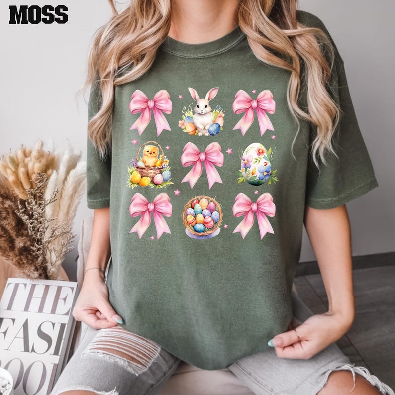Puede incluir: Una camiseta verde con un lazo rosa e ilustraciones de tem&aacute;tica de Pascua, incluyendo un conejito, pollitos y huevos.