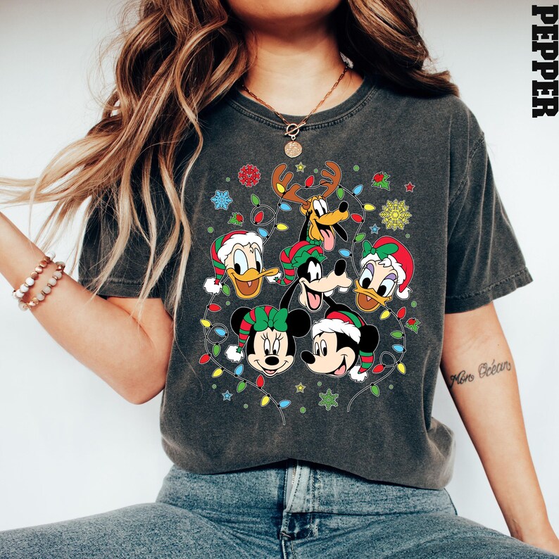 May include: A dark gray t-shirt with a Christmas-themed design featuring Mickey Mouse, Minnie Mouse, Donald Duck, Goofy, and Pluto. The characters are surrounded by colorful Christmas lights.