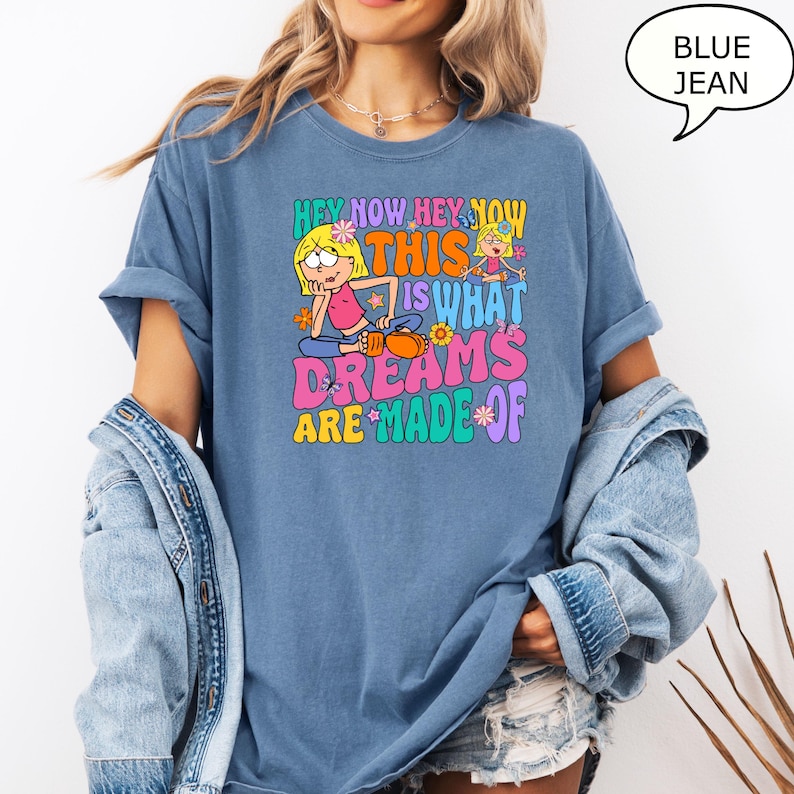 Może przedstawiać: Koszulka z niebieskiego dżinsu z kresk&oacute;wkową grafiką dw&oacute;ch dziewczynek i tekstem "Hey Now Hey Now This Is What Dreams Are Made Of".