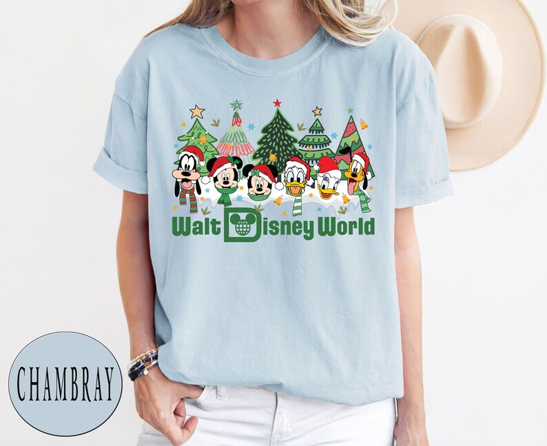 May include: Light blue t-shirt with a Christmas-themed design featuring Mickey Mouse, Minnie Mouse, Donald Duck, Goofy, and Pluto. The design includes Christmas trees, ornaments, and the text "Walt Disney World".
