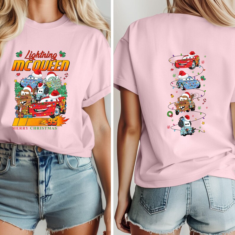 May include: A pale pink t-shirt with the words "Lightning McQueen" and a graphic of the character and other Cars characters wearing Christmas hats. The back of the shirt has a vertical design of the Cars characters with Christmas lights.