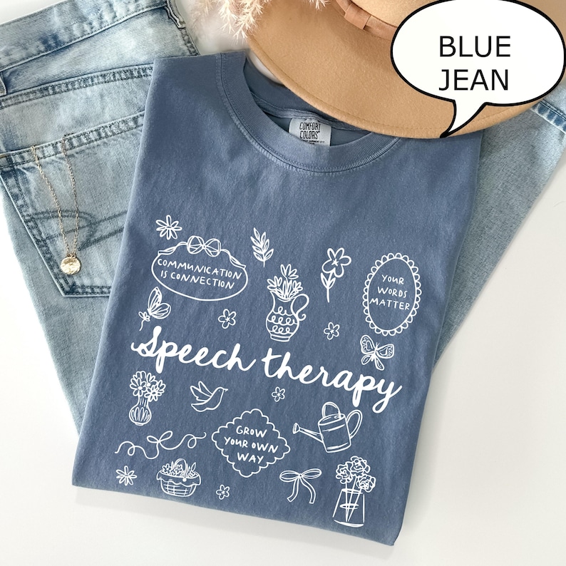 May include: A blue Comfort Colors t-shirt with the words "Speech therapy" and various white illustrations. The shirt is paired with blue jeans and a tan hat. The text "Blue Jean" is in a speech bubble.