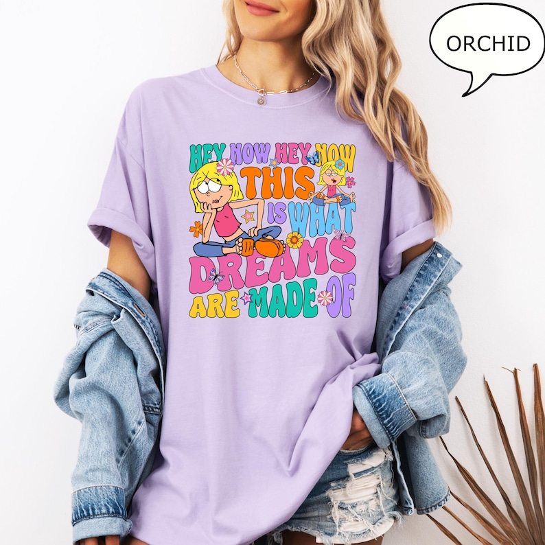 Może przedstawiać: Fioletowy t-shirt z nadrukiem graficznym przedstawiającym dwie kresk&oacute;wkowe dziewczyny i tekst "Hey Now Hey Now This Is What Dreams Are Made Of".
