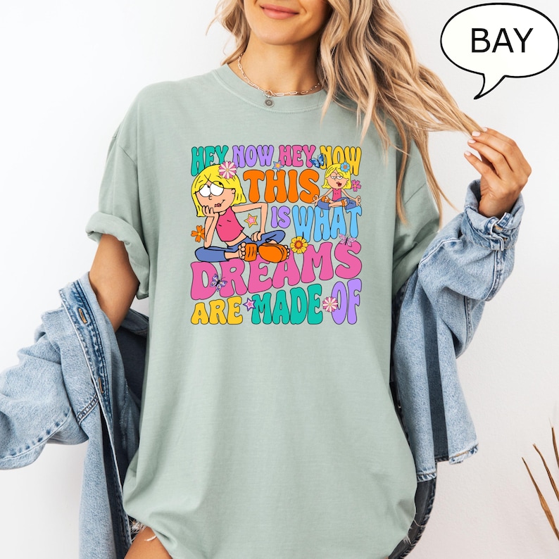 Może przedstawiać: Jasnozielony t-shirt z kolorowym nadrukiem graficznym przedstawiającym dziewczynkę z kresk&oacute;wki i tekst "Hey Now Hey Now This Is What Dreams Are Made Of".