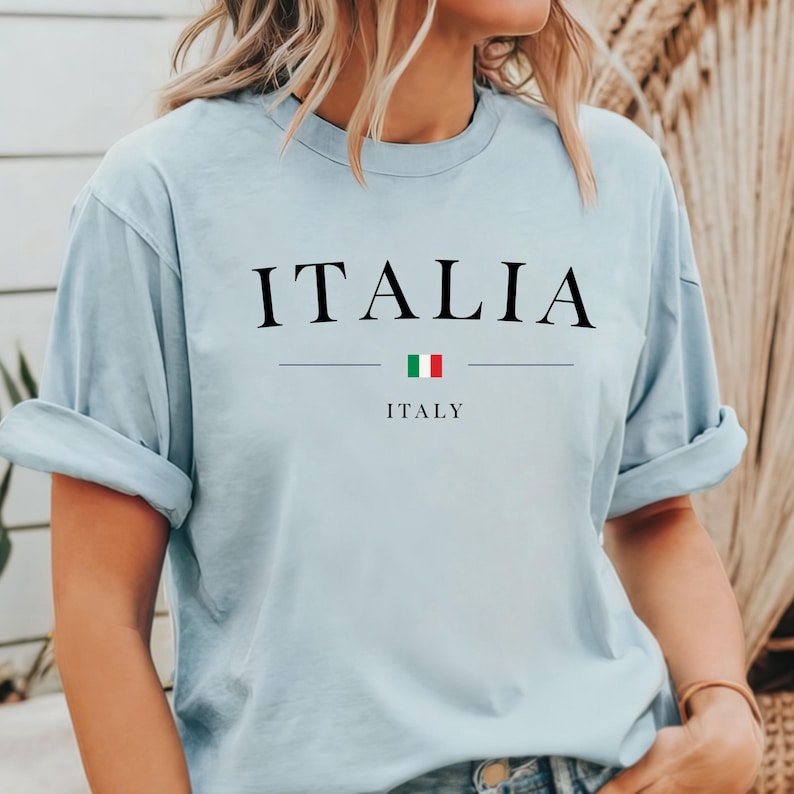 May include: Light blue t-shirt with the word "ITALIA" and the Italian flag printed on the front. The text "ITALY" is printed below the flag.