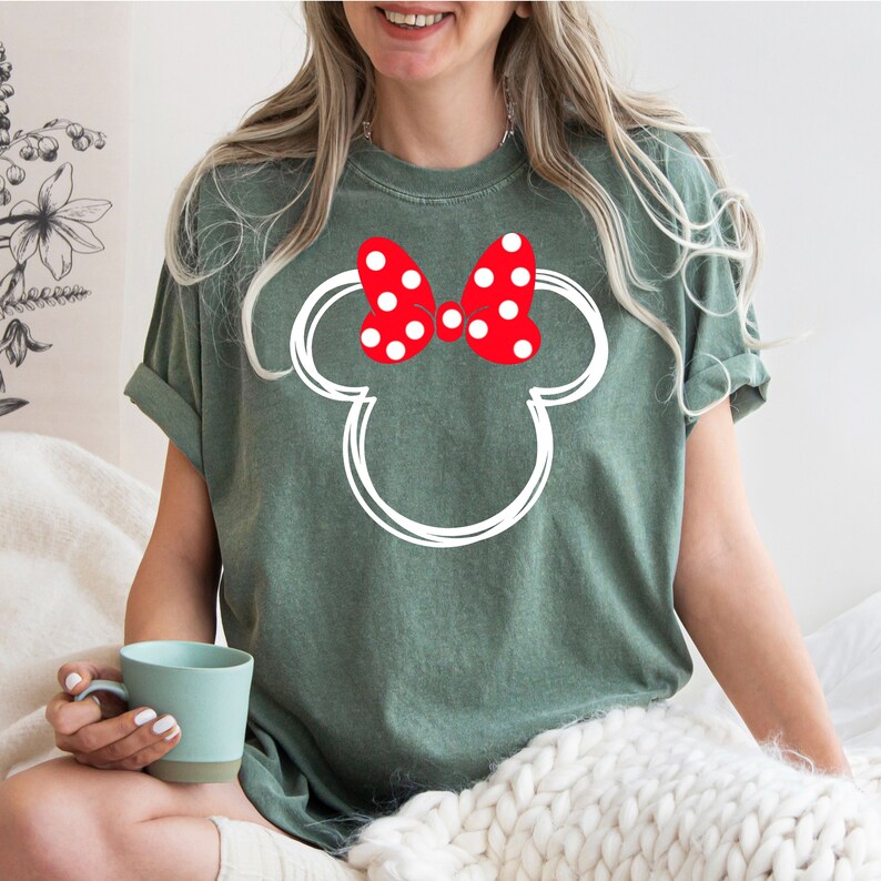 May include: A green t-shirt with a white outline of Mickey Mouse's head and a red bow with white polka dots.