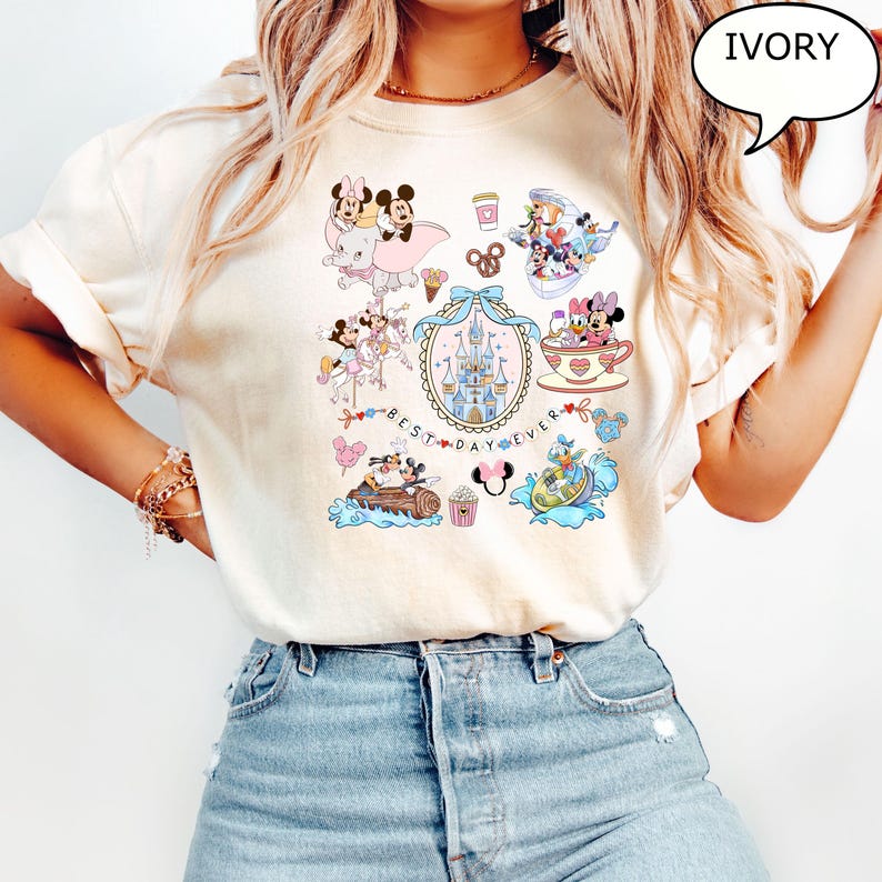 Puede incluir: Camiseta de color marfil con gr&aacute;ficos coloridos de personajes de Disney. El dise&ntilde;o incluye Mickey y Minnie Mouse, un castillo y el texto "BEST DAY EVER". Otros gr&aacute;ficos incluyen una taza de t&eacute;, un barco y un pretzel.