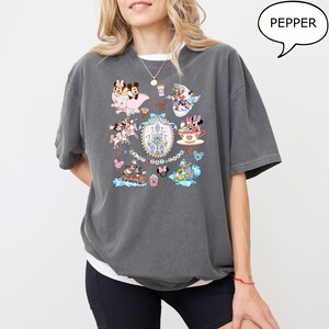 Puede incluir: Una camiseta gris carb&oacute;n con un gr&aacute;fico colorido de varios personajes de Disney y el texto "Best Day Ever". El dise&ntilde;o incluye im&aacute;genes de Mickey y Minnie Mouse, un castillo y otros elementos ic&oacute;nicos. La camiseta tiene un corte relajado.