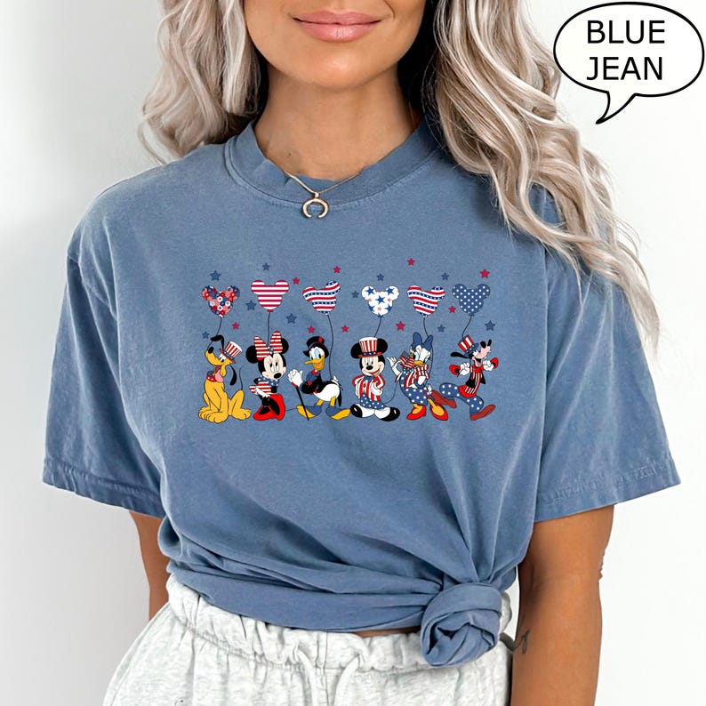 Puede incluir: Camiseta azul vaquero con personajes de dibujos animados sosteniendo globos en forma de coraz&oacute;n con patrones rojos, blancos y azules. Los personajes incluyen a Pluto, Minnie Mouse, Pato Donald, Mickey Mouse, Daisy Duck y Goofy.