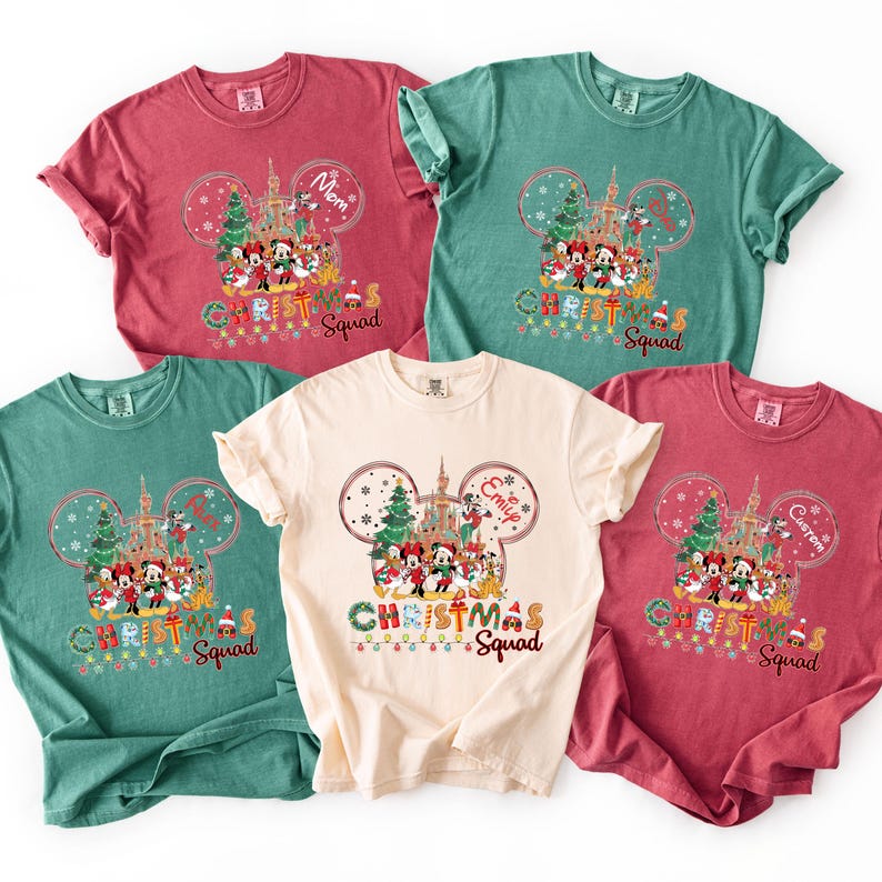 May include: Five colorful t-shirts with a Christmas theme. Each shirt features a Mickey Mouse-shaped design with a castle, Christmas characters, and the words "Christmas Squad." The shirts are in red, green, and cream colors.