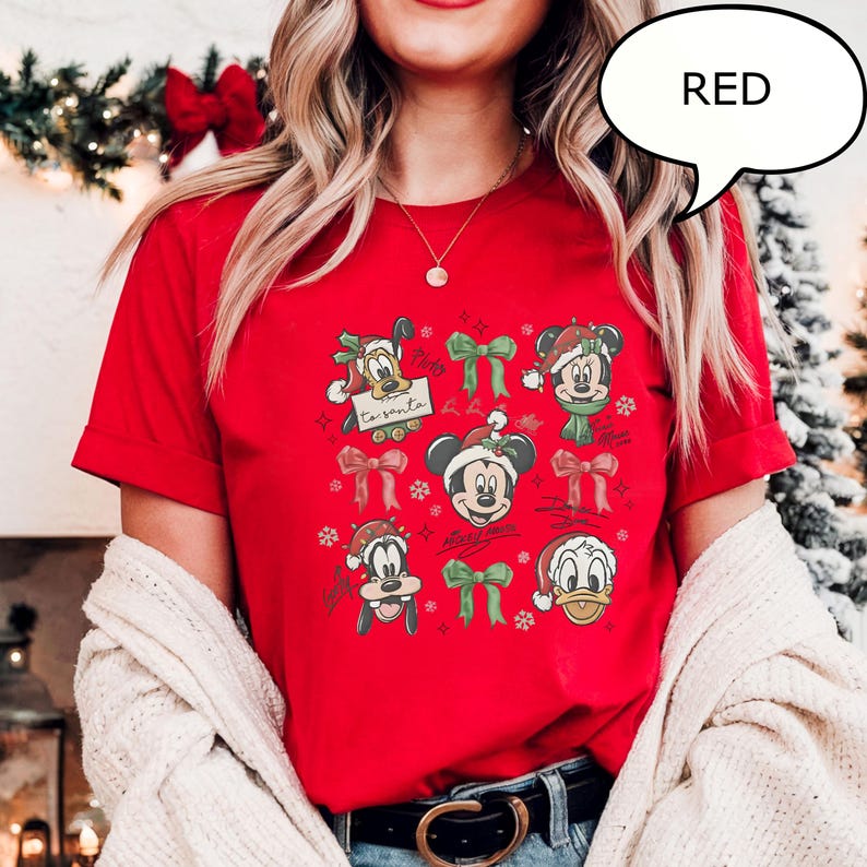 Puede incluir: Camiseta roja con personajes de dibujos animados con atuendos navide&ntilde;os. El dise&ntilde;o incluye a Mickey Mouse, el Pato Donald y Pluto, con el texto "to santa". La camiseta tiene cuello redondo y mangas cortas.