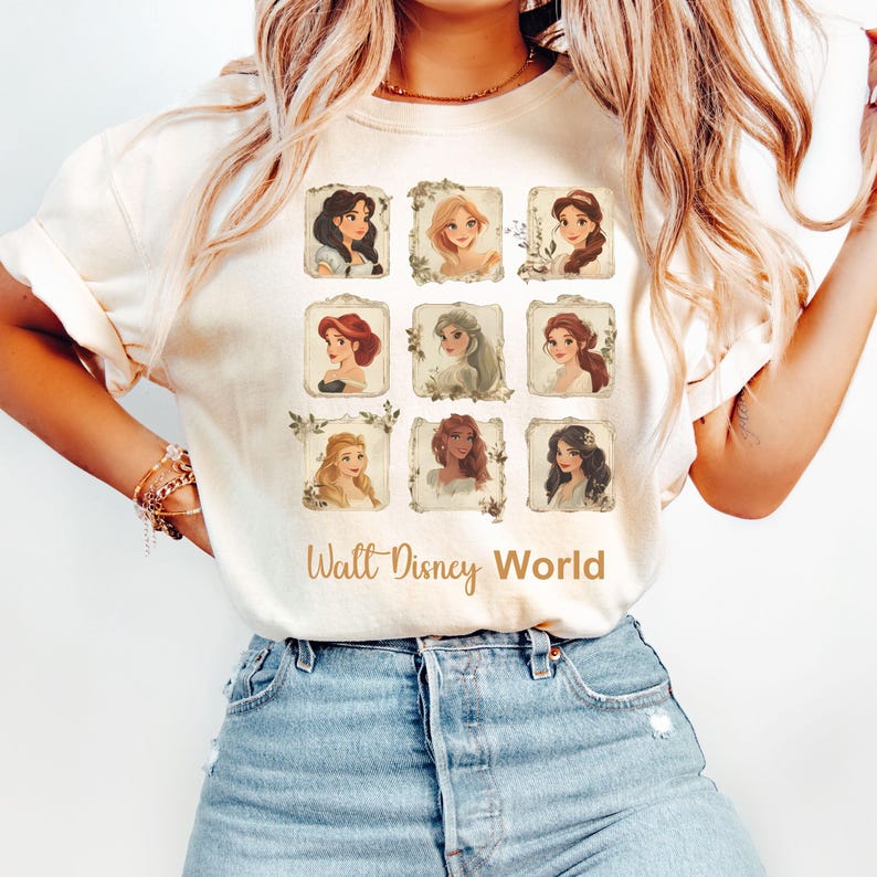 May include: White t-shirt with a vintage-style design featuring nine portraits of Disney princesses in frames with floral accents. The text "Walt Disney World" is printed below the portraits.
