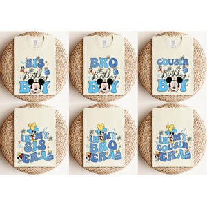 May include: Six cream-colored t-shirts with a Mickey Mouse design. The shirts feature the text "Sis Birthday Boy", "Bro Birthday Boy", "Cousin Birthday Boy", "In My Sis Era", "In My Bro Era", and "In My Cousin Era".