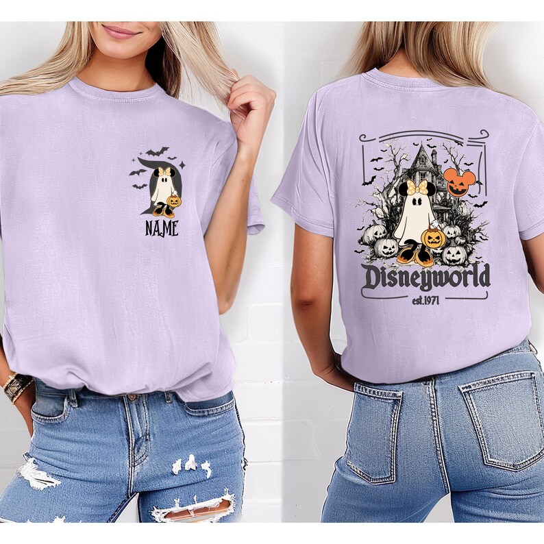 Pu&ograve; includere: T-shirt lilla con un design a tema Halloween. La parte anteriore presenta un fantasma con una zucca e la scritta "NAME". Il retro presenta una casa stregata, Mickey Mouse, zucche e la scritta "Disneyworld est.1971".