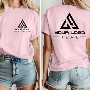 May include: A pink t-shirt with short sleeves and a black triangle logo on the front and back. The logo says "YOUR LOGO HERE" in black text.