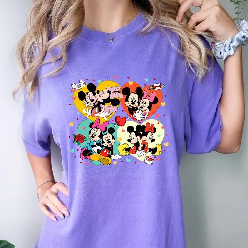 Puede incluir: Camiseta morada con un estampado gr&aacute;fico de Mickey Mouse y Minnie Mouse en cuatro marcos en forma de coraz&oacute;n. Los corazones est&aacute;n llenos de lunares y corazones de colores.