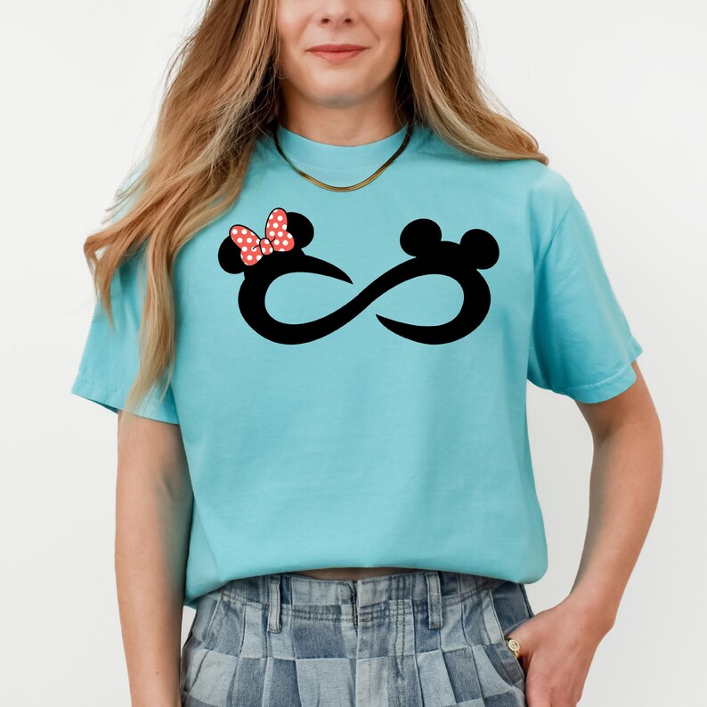 K&ouml;nnte beinhalten: Ein hellblaues T-Shirt mit einem schwarzen Unendlichkeits-Symbol-Design. Das Unendlichkeits-Symbol ist mit einer roten Schleife mit wei&szlig;en Punkten und einer schwarzen Silhouette von Mickey Mauses Kopf verziert.