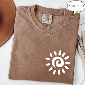 May include: A brown t-shirt with a white sun graphic and the text "COMFORT COLORS" on the tag. The shirt is labeled "ESPRESSO".