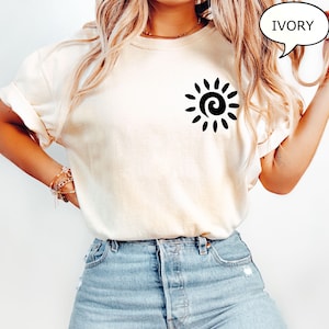 May include: A white t-shirt with a black sun graphic on the left chest. The text "IVORY" is in a speech bubble in the top right corner of the image.