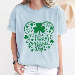 May include: Light blue t-shirt with a green shamrock and Mickey Mouse ears design. The text "Happy St. Patrick's Day" is printed on the shirt.