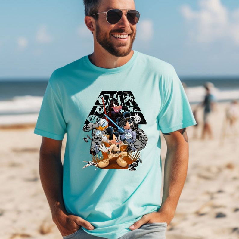 May include: A turquoise blue t-shirt with a black and white graphic print of Mickey Mouse, Donald Duck, and Goofy dressed as Star Wars characters. The graphic includes the text "STAR WARS" and the Death Star symbol.