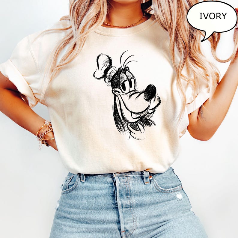 Puede incluir: Una camiseta blanca con un boceto en blanco y negro de la cara de Goofy en la parte delantera. El texto "IVORY" est&aacute; en un bocadillo de di&aacute;logo en la esquina superior derecha de la imagen.