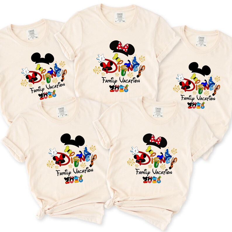 May include: Five cream-colored t-shirts with a Disney-themed graphic. Each shirt features a Mickey Mouse head, the word "Disney" in colorful letters, and the text "Family Vacation 2026".