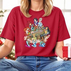 May include: Red t-shirt featuring a graphic of Disney princesses in front of the Epcot logo. The princesses include Snow White, Cinderella, Ariel, Belle, Tiana, and Mulan.
