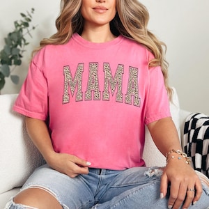 May include: Pink t-shirt with a large "MAMA" graphic in a leopard print design.