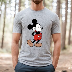 Op de afbeelding: Een grijs T-shirt met een zwart-witte afbeelding van Mickey Mouse met een rode broek.