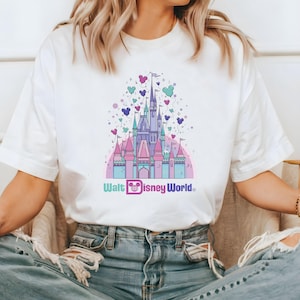May include: White t-shirt with a pink and blue illustration of Cinderella's castle with balloons and the text "Walt Disney World".