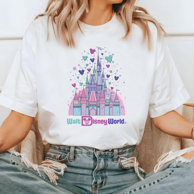 May include: White t-shirt with a pink and blue illustration of Cinderella's castle with balloons and the text "Walt Disney World".
