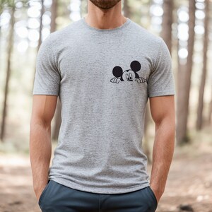 May include: A gray t-shirt with a black and white cartoon image of Mickey Mouse peeking out from behind the shirt.