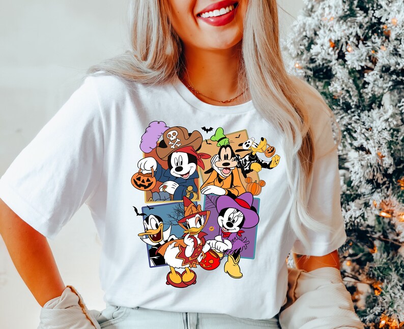 K&ouml;nnte beinhalten: Wei&szlig;es T-Shirt mit einem bunten Grafikdruck von Mickey Mouse und seinen Freunden in Halloween-Kost&uuml;men. Zu den Charakteren geh&ouml;ren Mickey Mouse, Minnie Mouse, Donald Duck, Goofy und Pluto.
