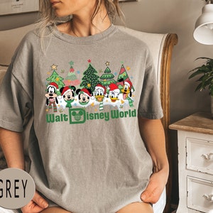 May include: A grey t-shirt with a Christmas-themed design featuring Mickey Mouse, Donald Duck, Goofy, and Pluto in front of Christmas trees. The text "Walt Disney World" is printed below the characters.