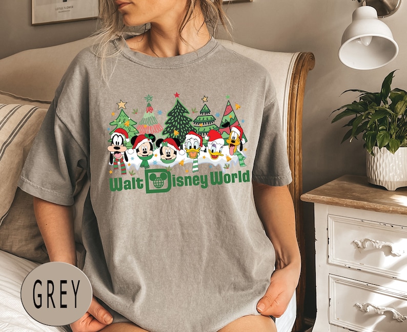 May include: A grey t-shirt with a Christmas-themed design featuring Mickey Mouse, Donald Duck, Goofy, and Pluto in front of Christmas trees. The text "Walt Disney World" is printed below the characters.