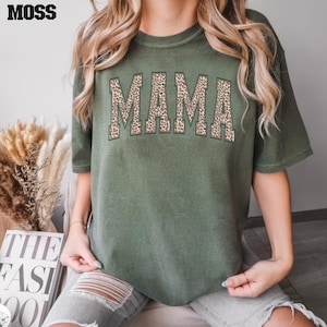 May include: A green t-shirt with the word "MAMA" printed in brown and black leopard print.