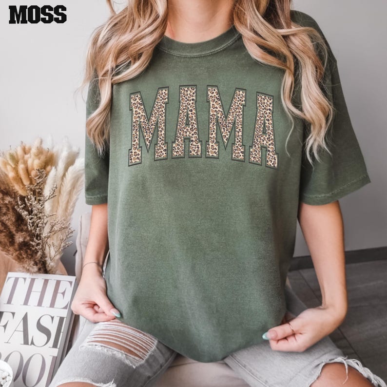 May include: A green t-shirt with the word "MAMA" printed in brown and black leopard print.