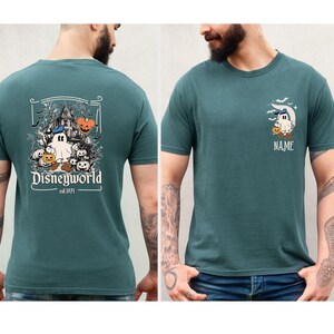 Pu&ograve; includere: T-shirt verde acqua a maniche corte con un design Disneyworld. La grafica sul retro include una casa stregata, un fantasma, zucche e la scritta "Disneyworld est. 1971". La parte anteriore presenta un fantasma, una luna, pipistrelli e la scritta "NAME".