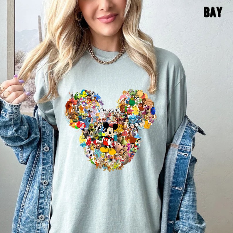 May include: A light blue t-shirt with a graphic of Mickey Mouse's head made up of various Disney characters. The characters are colorful and include Mickey Mouse, Minnie Mouse, Donald Duck, Goofy, and many more.