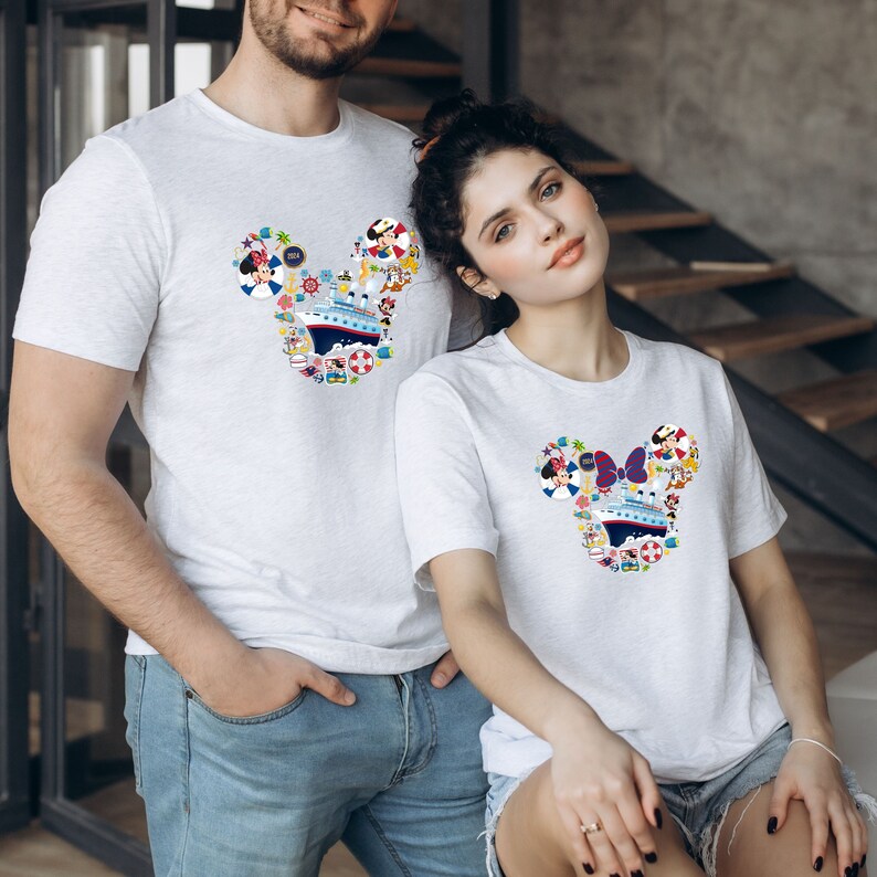 Pu&ograve; includere: T-shirt grigie chiare abbinate con un design a forma di testa di Topolino riempito di elementi nautici e dei cartoni animati. Il design include una nave da crociera, Minnie Mouse e altre grafiche a tema vacanza. Le magliette sono a maniche corte.