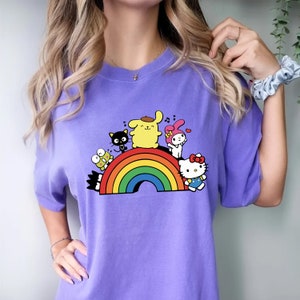 Pode incluir: Camiseta roxa com um arco-&iacute;ris e personagens de desenhos animados. Os personagens incluem Hello Kitty, My Melody, Keroppi e um personagem amarelo com boina.
