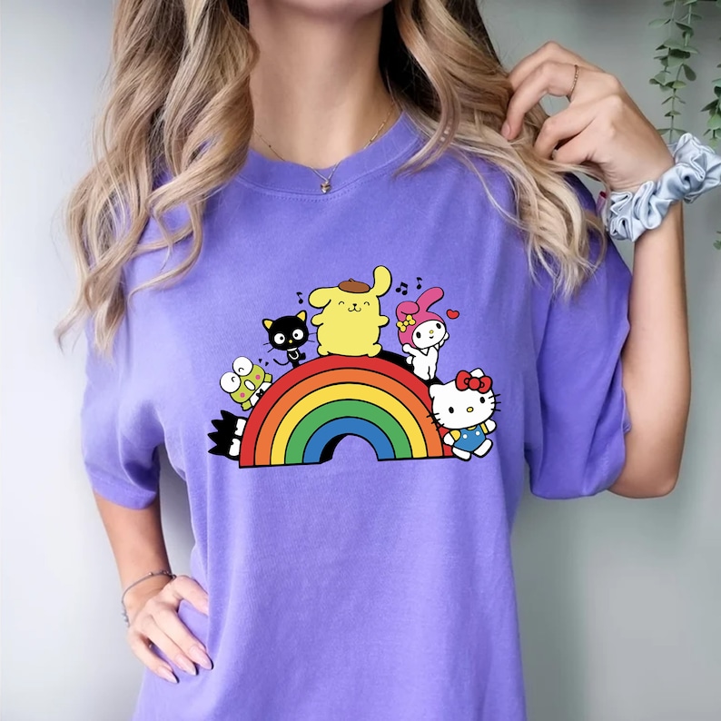 Pode incluir: Camiseta roxa com um arco-&iacute;ris e personagens de desenhos animados. Os personagens incluem Hello Kitty, My Melody, Keroppi e um personagem amarelo com boina.