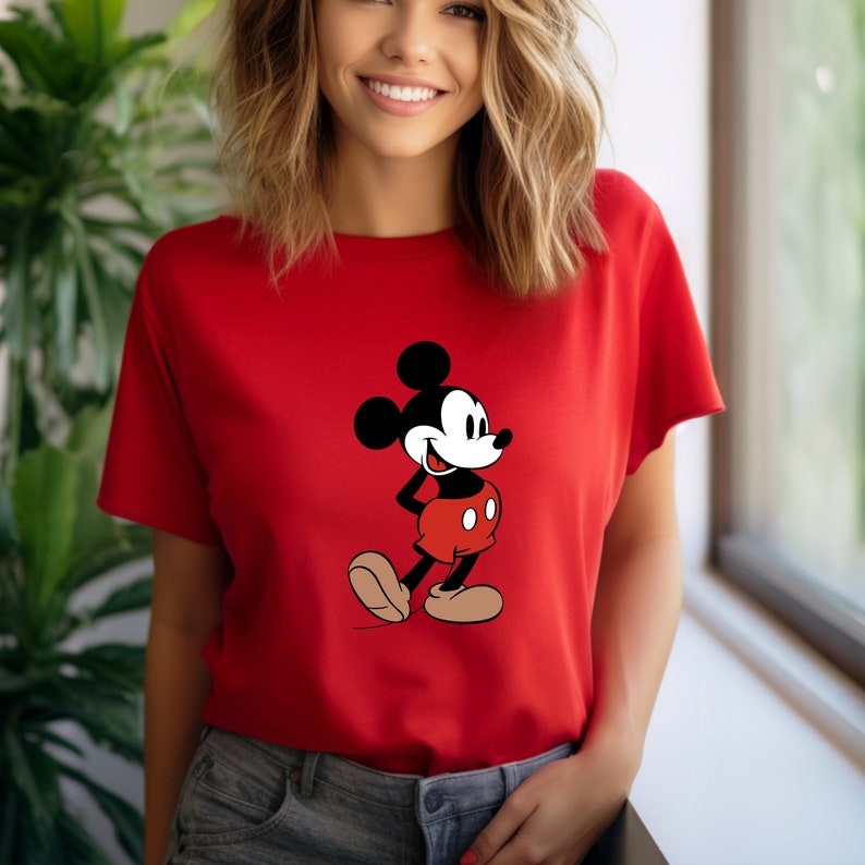 Op de afbeelding: Een rood T-shirt met een zwart-witte afbeelding van Mickey Mouse op de voorkant. Mickey Mouse draagt een rode broek en gele schoenen.