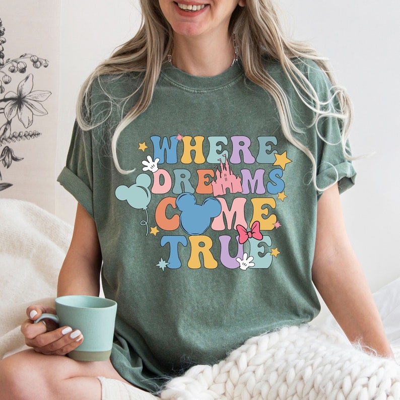 May include: Green t-shirt with a colorful graphic that says "Where Dreams Come True" with Mickey Mouse ears, a castle, and stars.