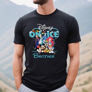 May include: Black t-shirt with a blue and white Disney on Ice graphic featuring Mickey Mouse, Minnie Mouse, Donald Duck, Goofy, and other Disney characters. The text "Brother" is below the graphic.